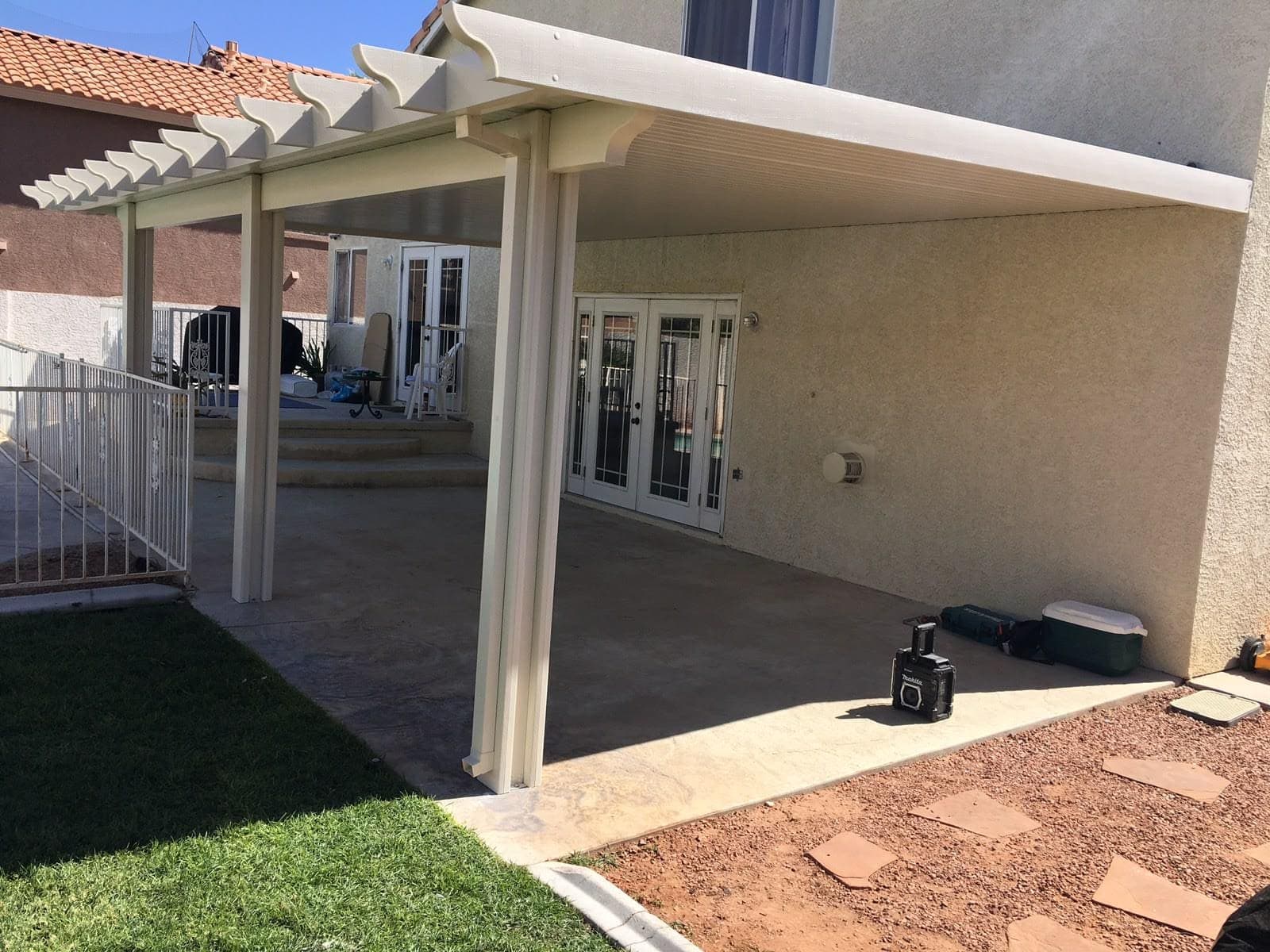 Solid patio cover on a tan home with a paver patio